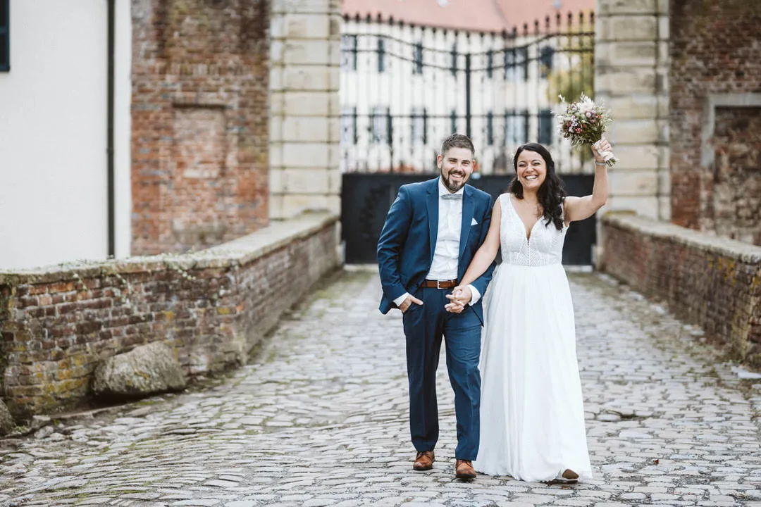 Ihr Hochzeitsfotograf Bielefeld fängt romantische Momente beim Paarshooting im Botanischen Garten Bielefeld ein. Die braut hält einen Brautstrauß in der hand und steht vor der schloß einfahrt